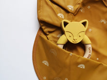 Load image into Gallery viewer, Mustard yellow fox ring silicone and beech baby teether poking out from a rainbow and mustard bib