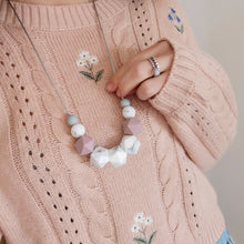 Load image into Gallery viewer, A mum wearing pink jumper and modelling a silicone teething necklace for breastfeeding in marble, mauve and grey.
