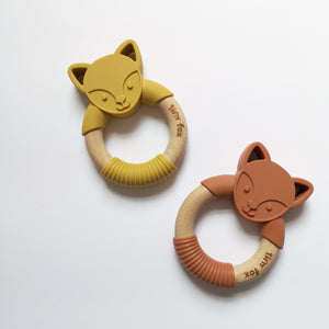Two silicone and beech teethers with cute fox faces on a white background